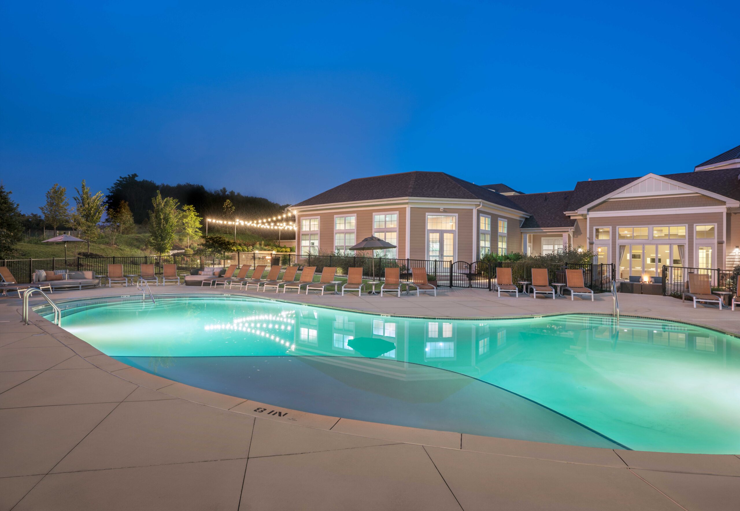 Parc Plymouth Meeting's pool during the evening with string lights and lounge seating