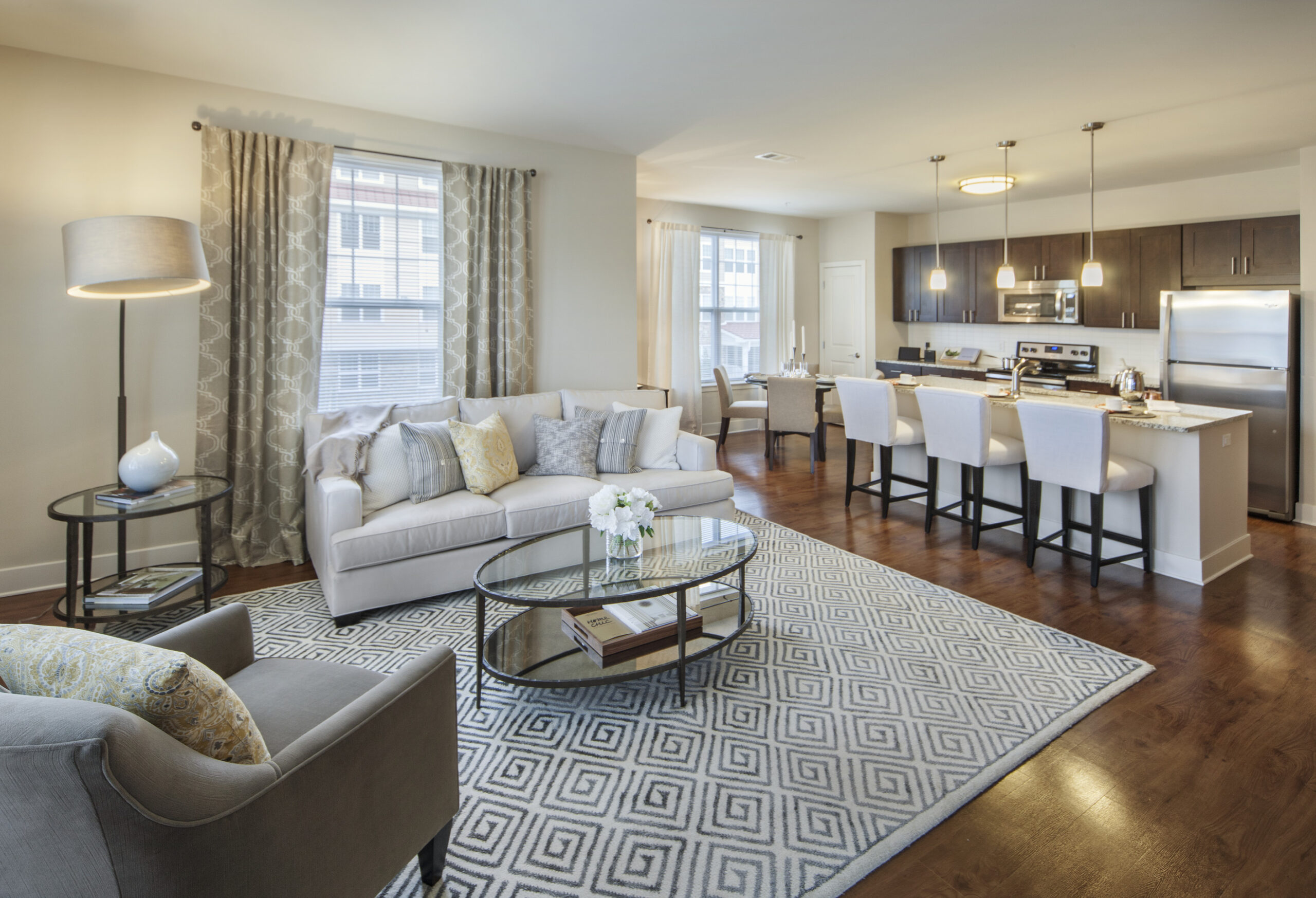 Model living room at Parc Plymouth Meeting with wood-style flooring, couches, and windows with ample natural light