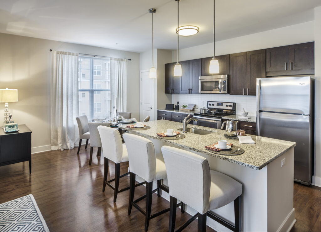 Model kitchen at Parc Plymouth Meeting with dark brown cabinets, pendant lighting, and breakfast bar seating