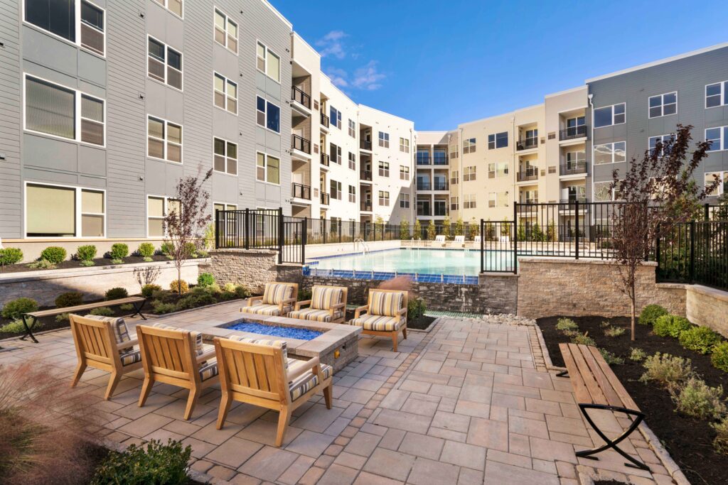 Outdoor lounge area with pool in background at Kensington Place