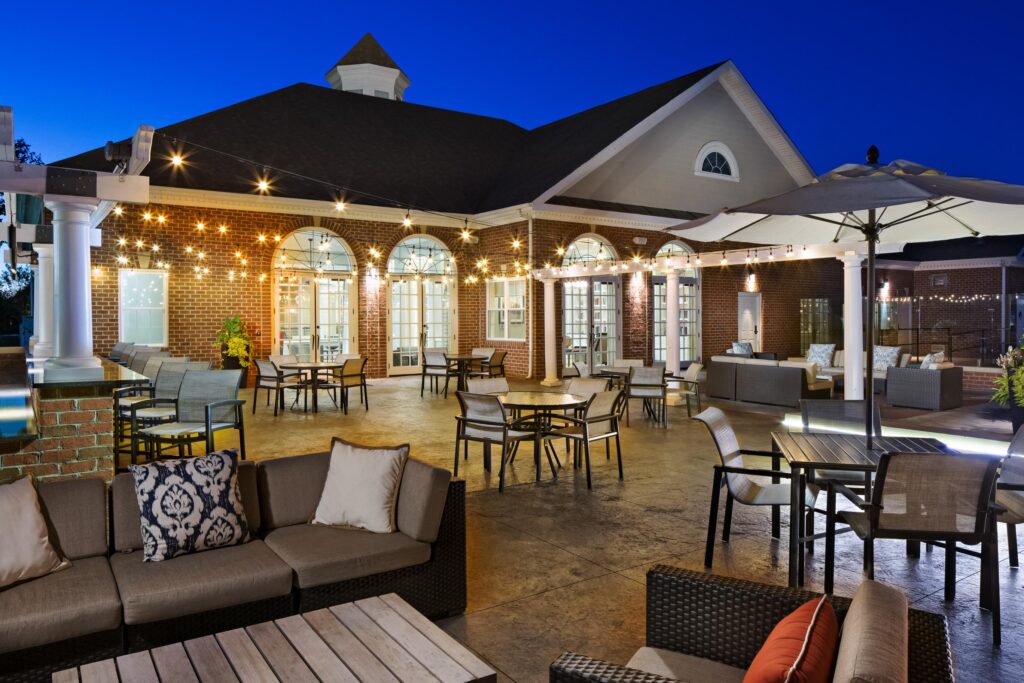 Outdoor lounge area with string lights at Dulles Greene at dusk