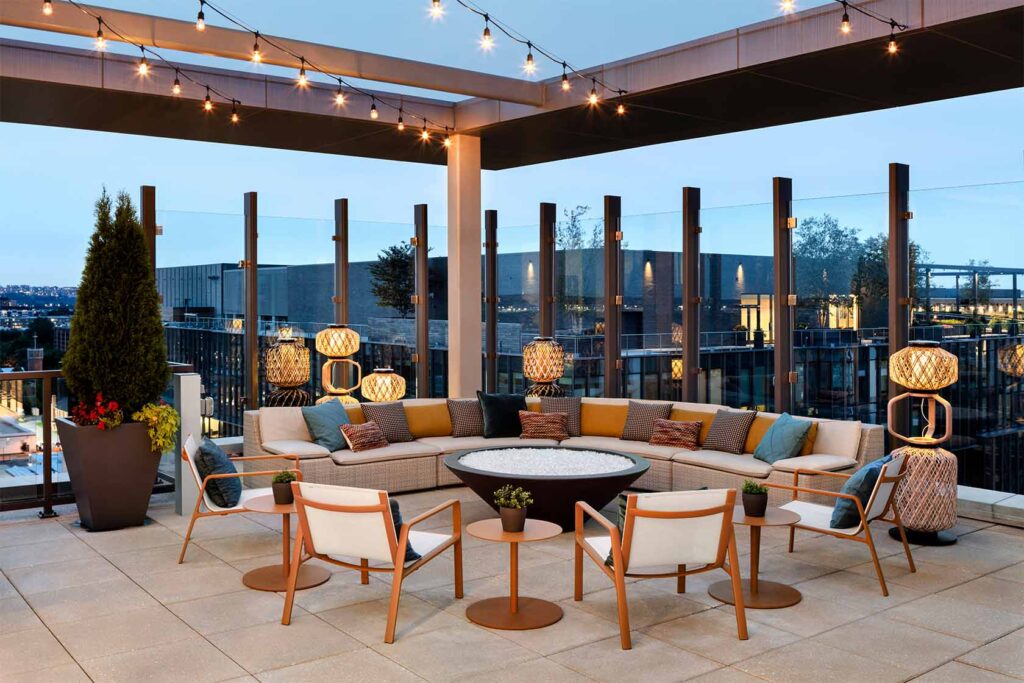 Rooftop lounge at Parc Riverside with fire pit, couch and chair seating, and strings of lights