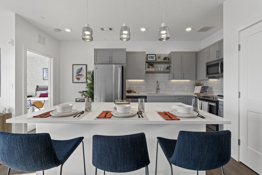 Three blue chairs and place settings at kitchen island at Emblem 120