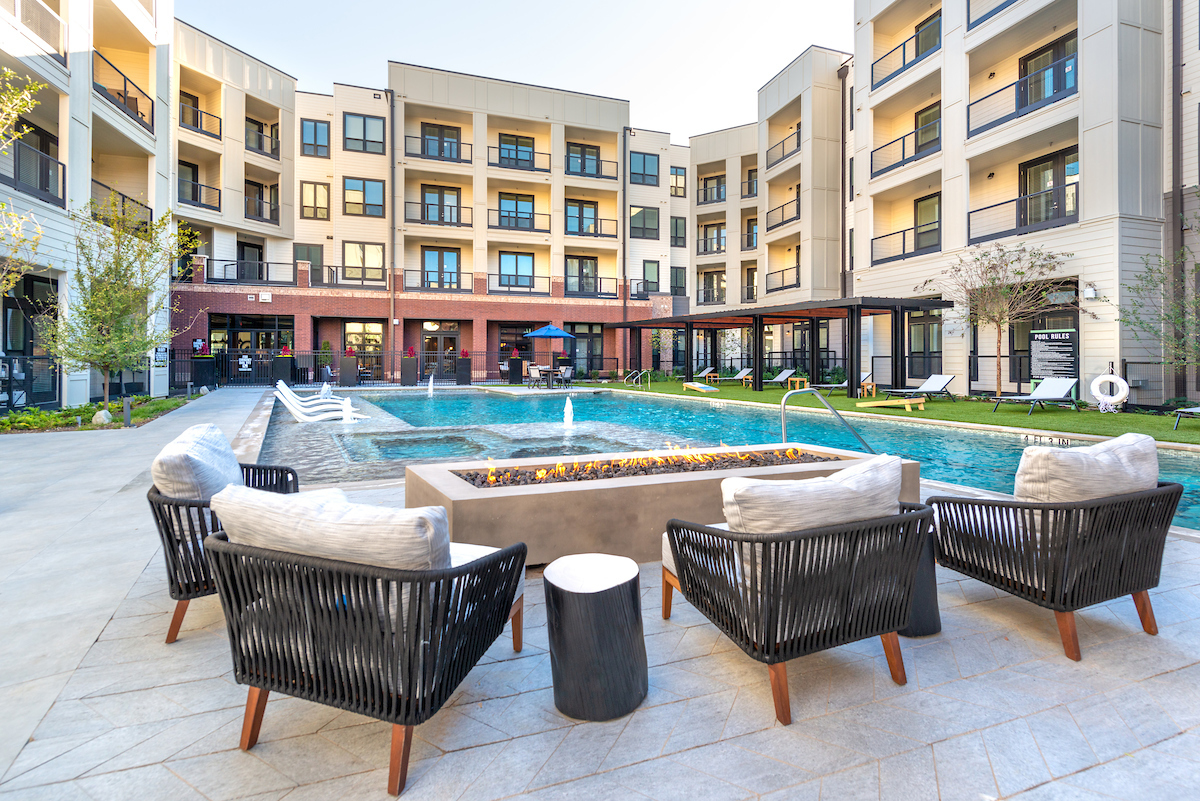 Outdoor lounge area with fire pit table and pool in background at Kilby