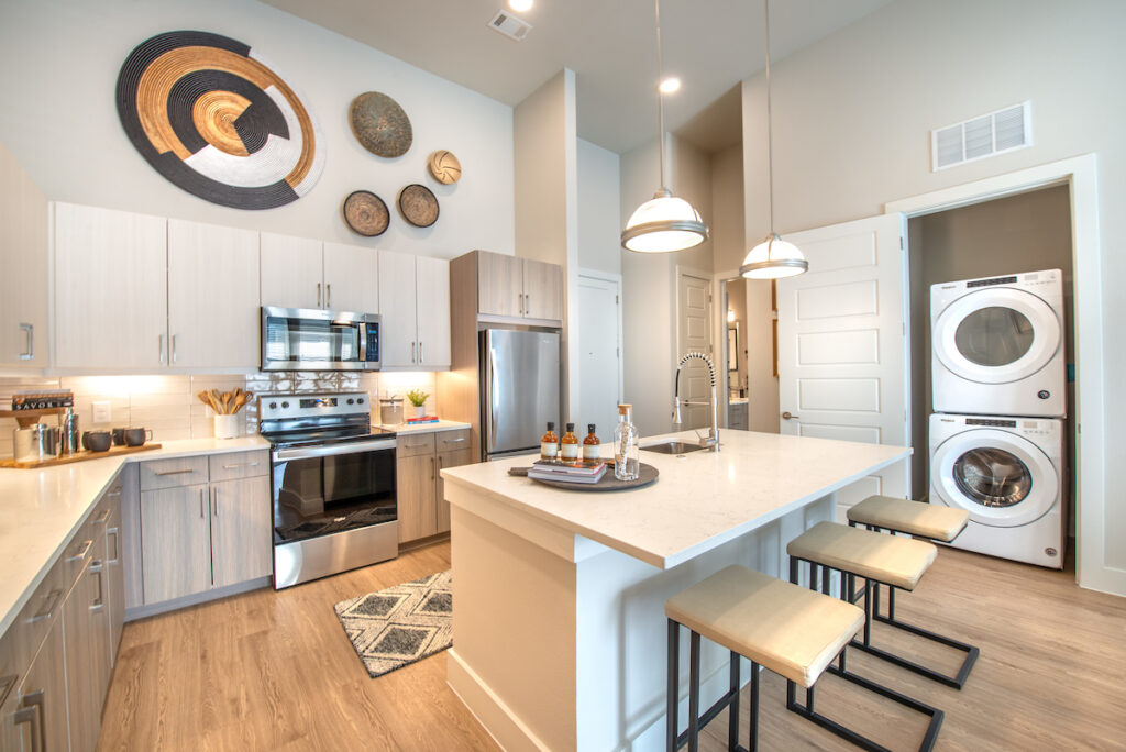 Modern kitchen with island seating and laundry area in background at Kilby