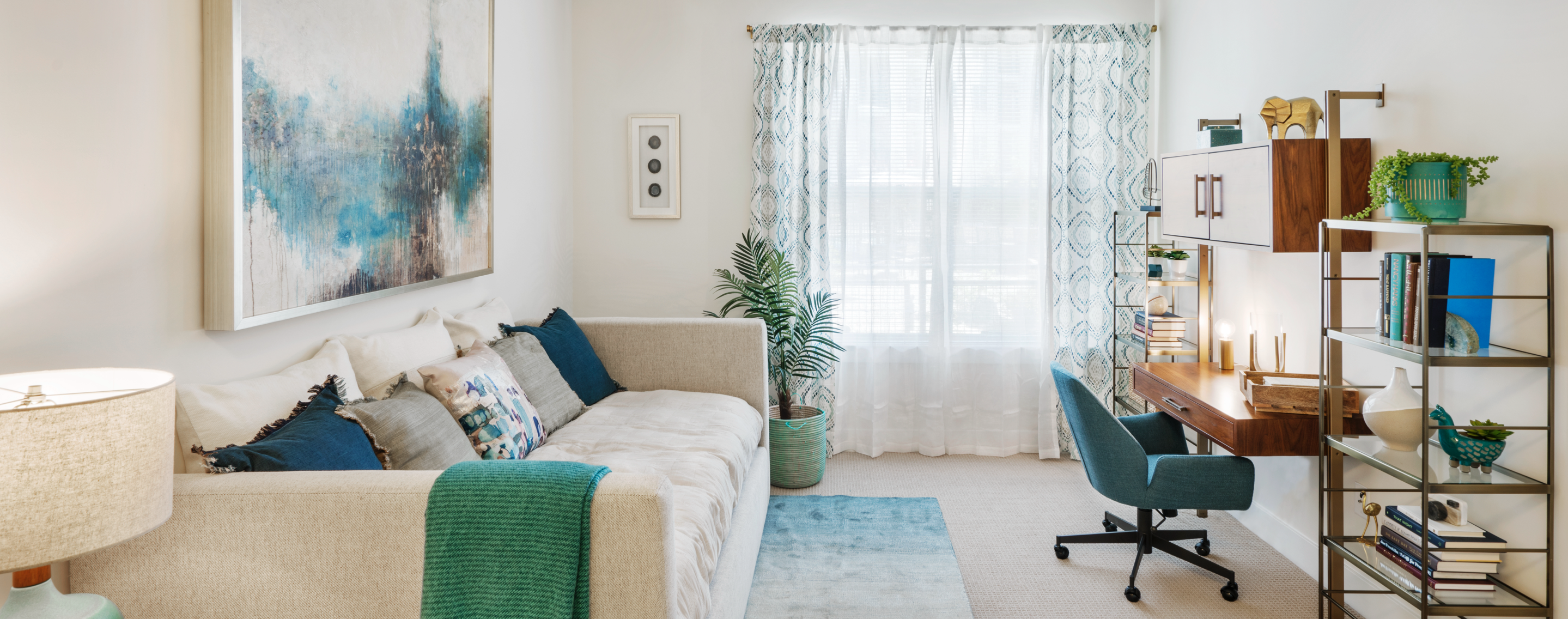 Beige couch, desk, chair and bookcase in living area