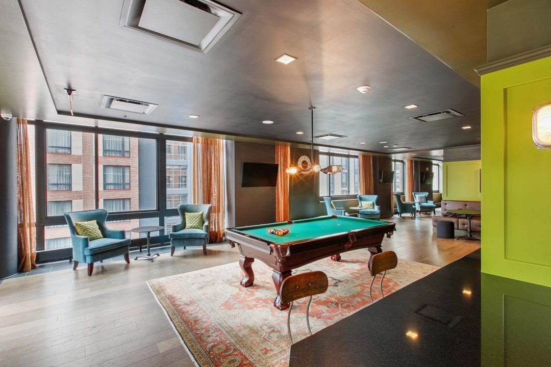Clubroom with pool table and seating areas for residents