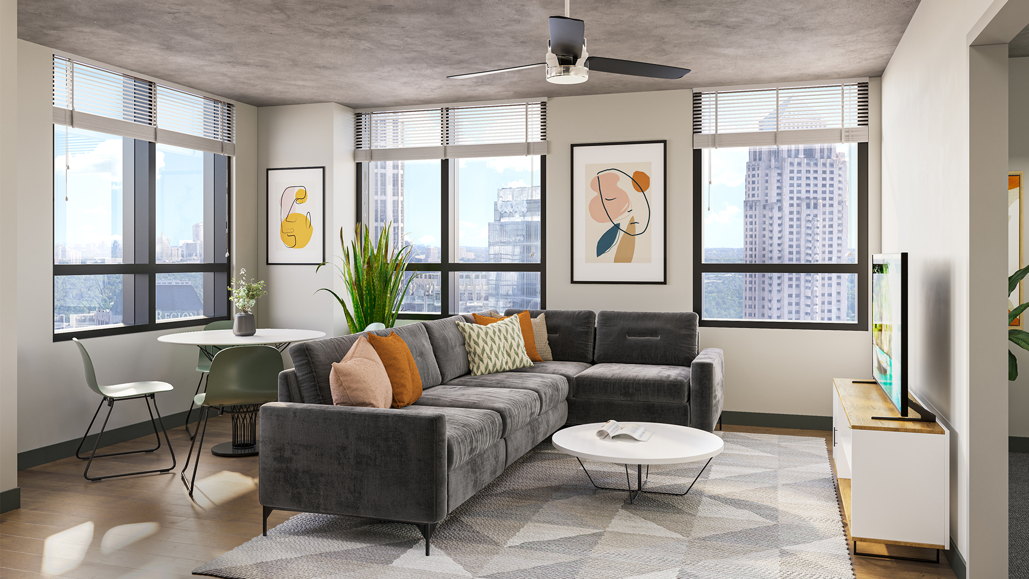 Apartment living room with large windows, ceiling fan, and gray couch. A table and chairs are in the corner behind the couch.
