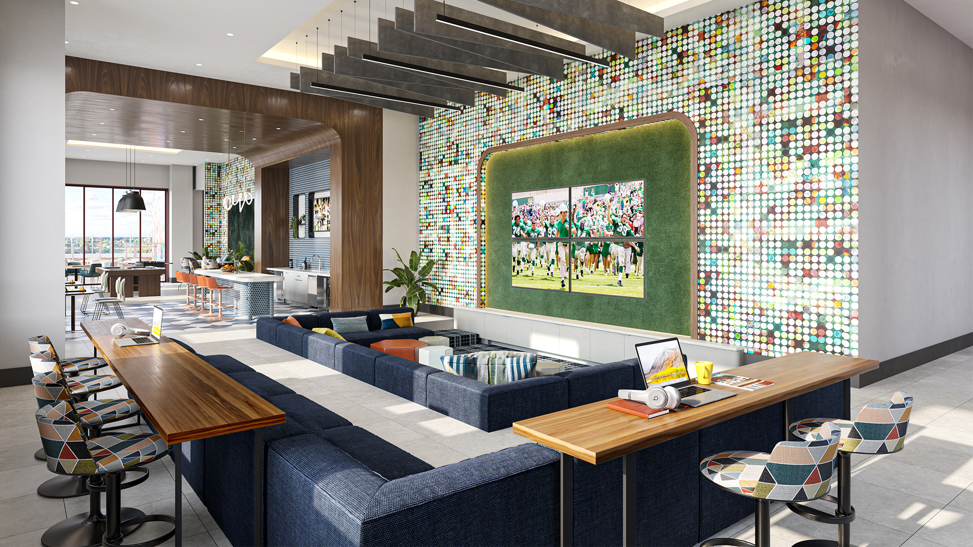 Resident lounge with large TV screens, blue couches, counter seating, and accent wall with a colorful circular pattern.